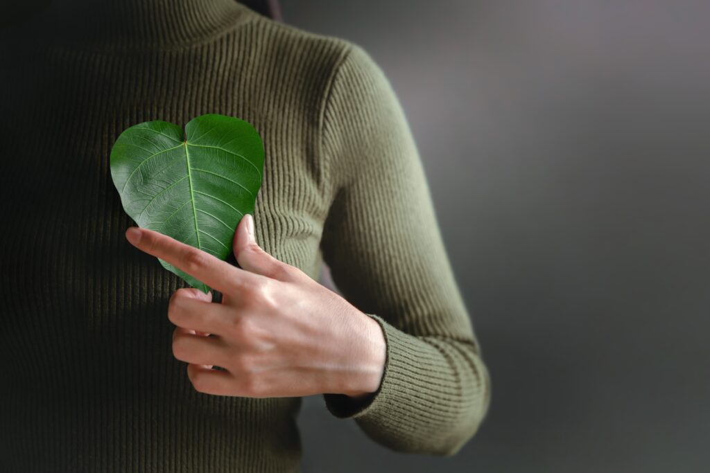 woman holding leaf over heart