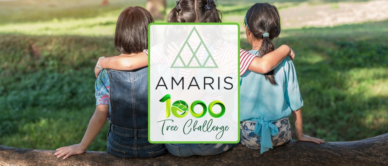 three young girls from behind sitting on fallen tree trunk, middle girl has her arm around the other two - amaris and 1000 tree challenge logos are infront