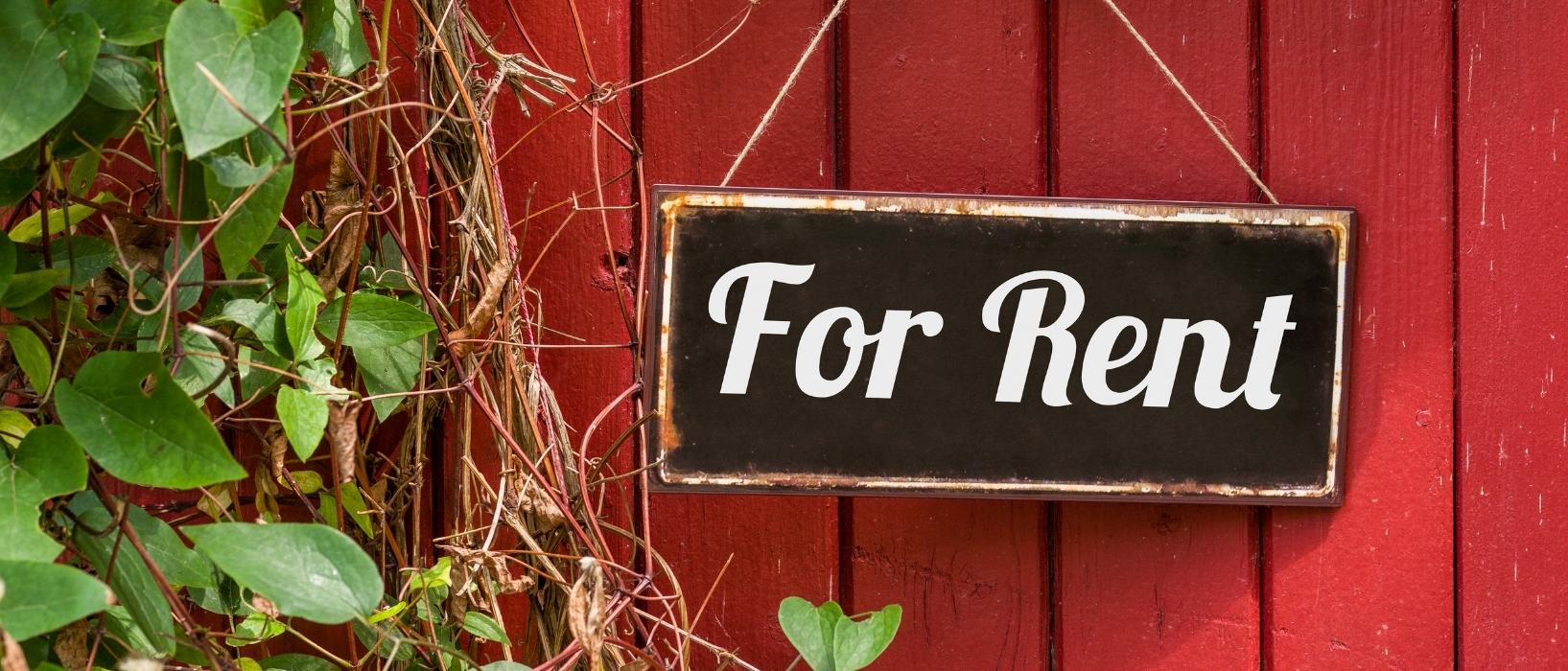 for rent sign hanging on red wooden wall with vines hanging on the side