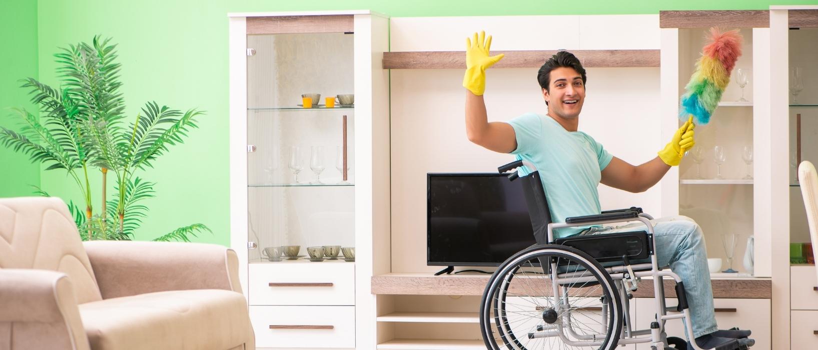 man in wheelchair and wearing yellow gloves holds up multicoloured duster inside his living room to show off sustainable cleaning products at home
