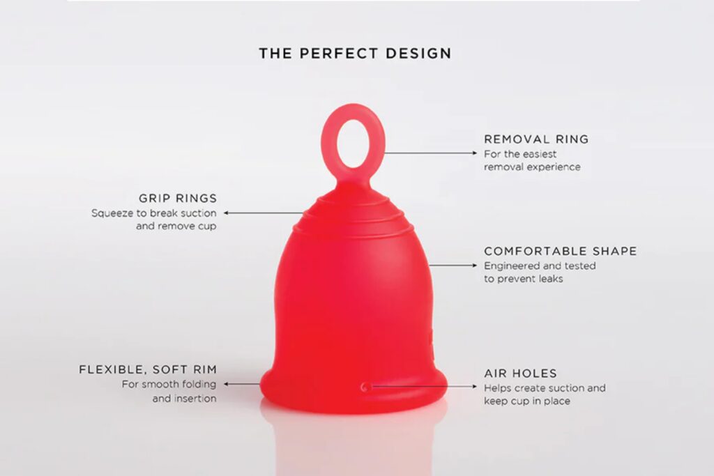red Asan menstrual cup placed upside down on white surface, it has a rubber ring attached to the bottom and black letters above read 'the perfect design'